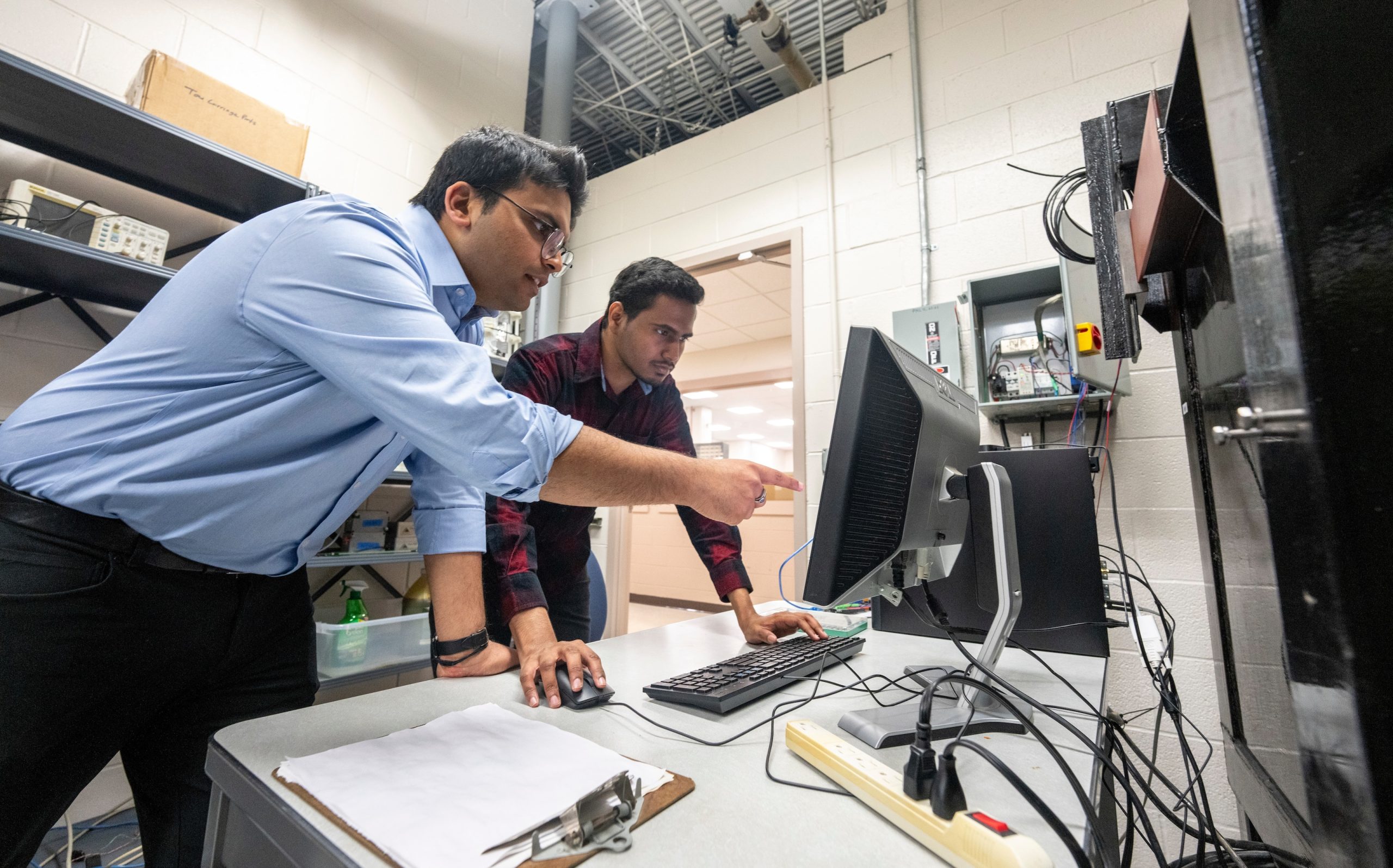 Two people pointing at a computer